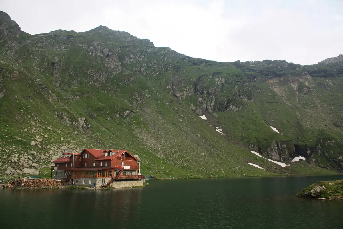 Mountain chalet on the shore of Bâlea Lake below steep green slopes