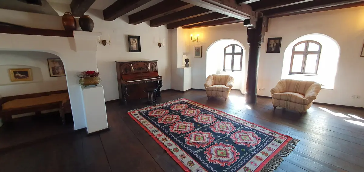Sitting room with a patterned carpet, armchairs and two arched windows
