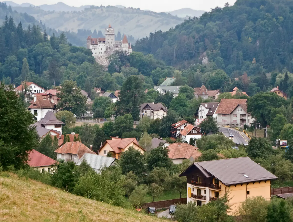 Houses of Bran village among green hills with the castle on the ridge