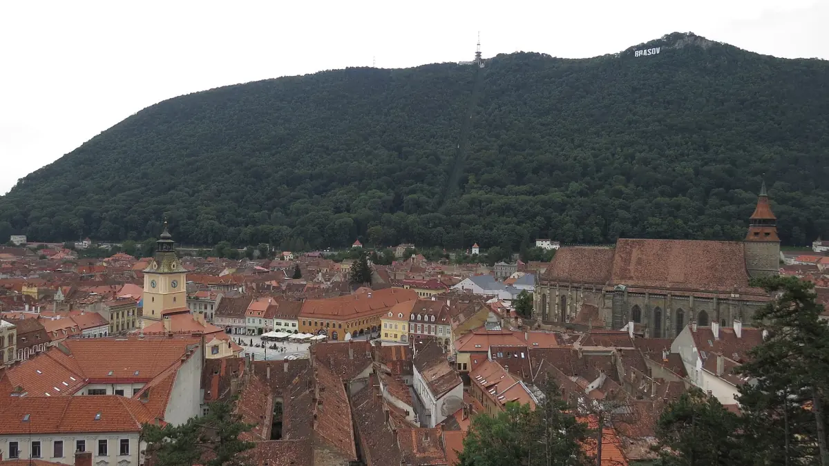 Red roofs of Brașov below the dark forested slope of Tâmpa mountain