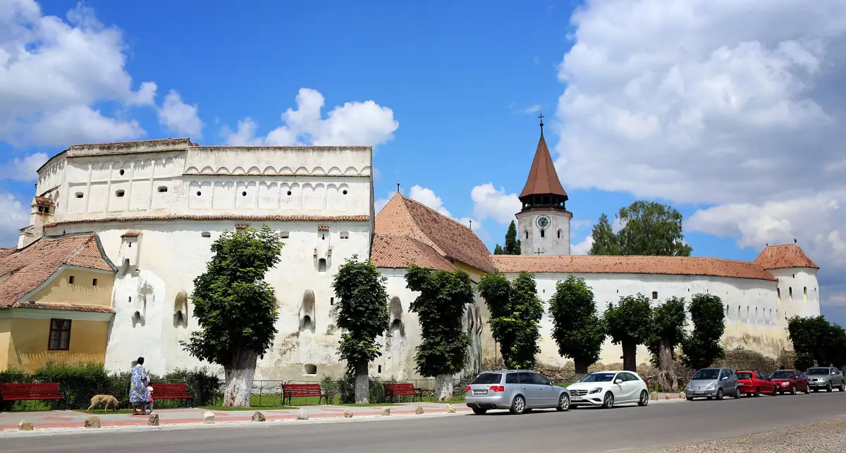 White fortified church with thick walls and a small tower in a village