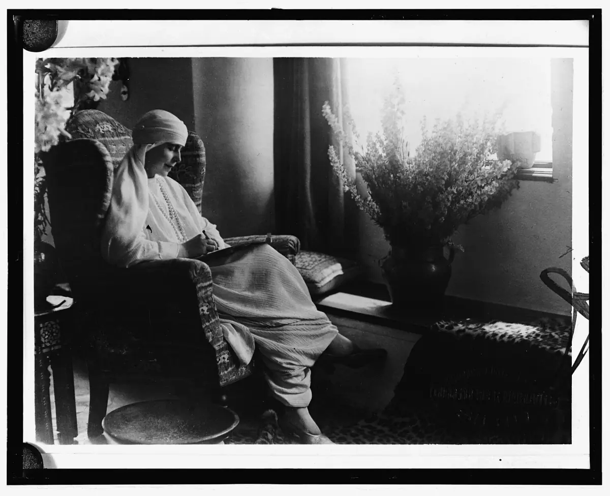 Historic black and white photograph of a seated woman beside a bright window